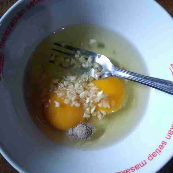 Kocok telur bersama garam, merica, dan bawang putih menggunakan garpu.