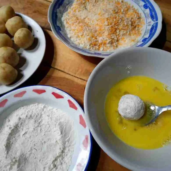 Gulingkan bola-bola pada tepung terigu kemudian celupkan dalam kocokan telur lalu balut rata dengan tepung roti, lakukan hingga selesai.