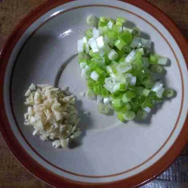 Iris tipis daun bawang dan cincang bawang putih.