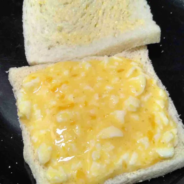 Isi roti dengan telur. Potong segitiga. Sajikan.