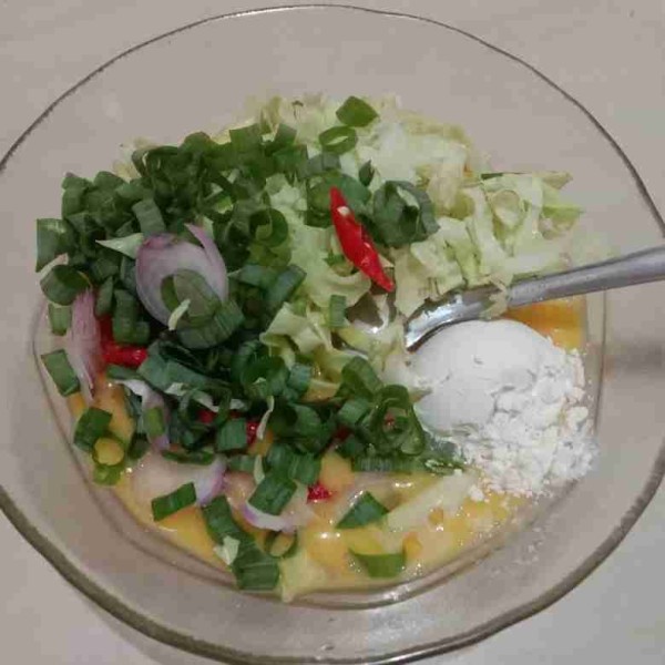 Kocok lepas telur lalu masukkan irisan daun bawang, bawang merah, daun kol, tepung terigu, garam, dan merica bubuk lalu aduk rata.