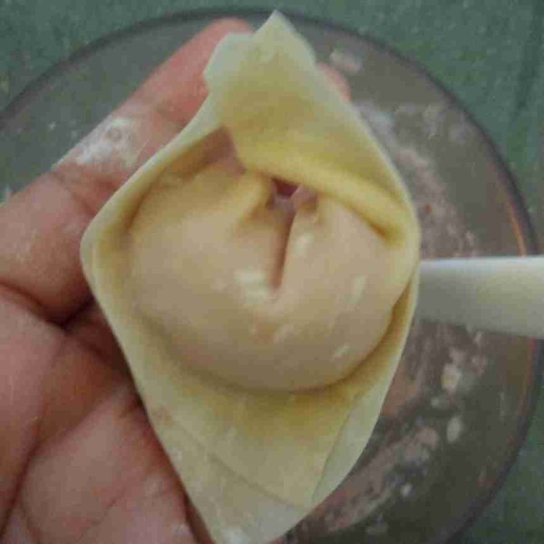 Ambil 1 sendok teh daging cincang diujung kulit pangsit. Gulung lalu rekatkan bagian 2 ujung pangsit, lakukan sampai selesai.