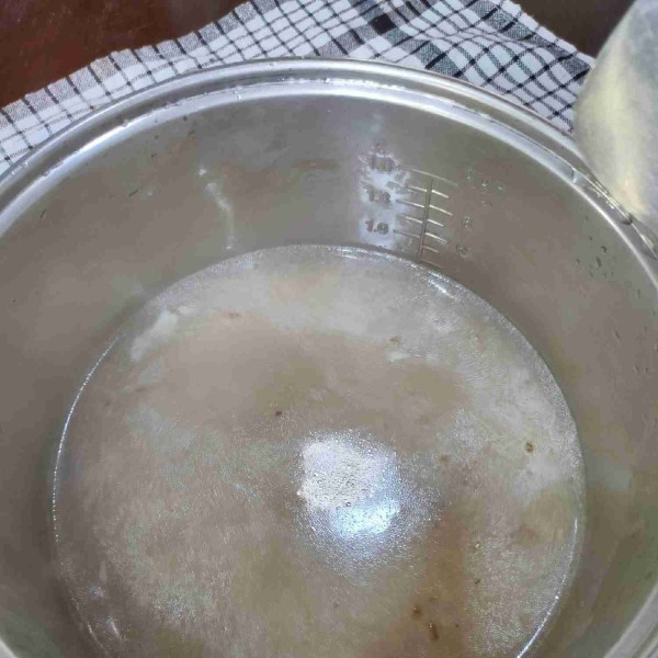 Tuang beras dan air rebusan ayam ke dalam panci rice cooker.