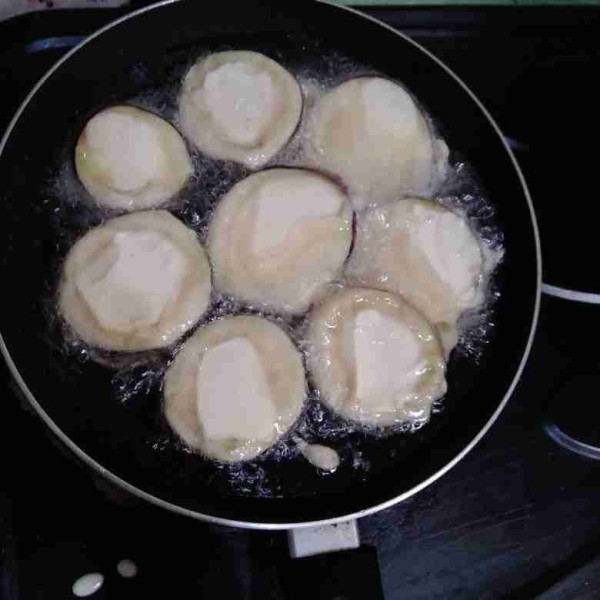 Kentalkan tepung serbaguna, celupkan terong hingga terbalut rata.Ggoreng dengan api sedang.