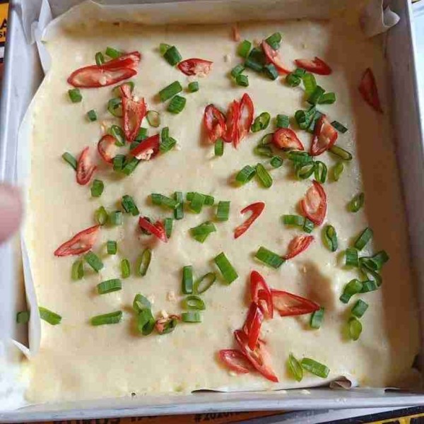 Tuang adonan ke dalam loyang yang sudah di alasi dengan kertas roti dan olesan margarin,taburi dengan daun bawang dan cabe.