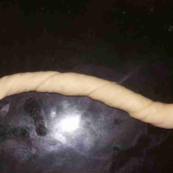 Bagi adonan menjadi 16 bagian. Ambil satu bagian, pulung adonan hingga memanjang. Setelah itu, pulung kembali kedua ujungnya dengan arah berlawanan.