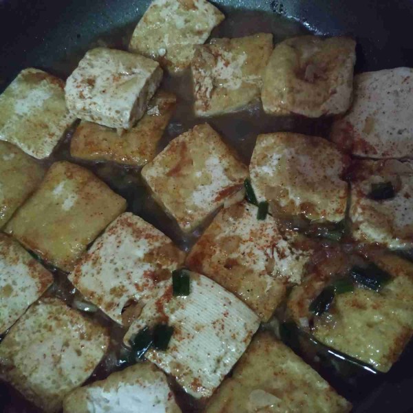 Masukkan tahu goreng, masak kembali sampai kuah menyusut dan menyerap, koreksi rasa. Tambahkan minyak wijen, angkat dan sajikan dengan taburan wijen sangrai dan irisan daun bawang.
