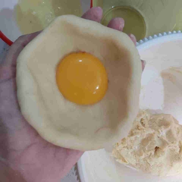 Sendokan kuning telur dan sedikit putih telur, masukkan ke dalam lubang adonan.