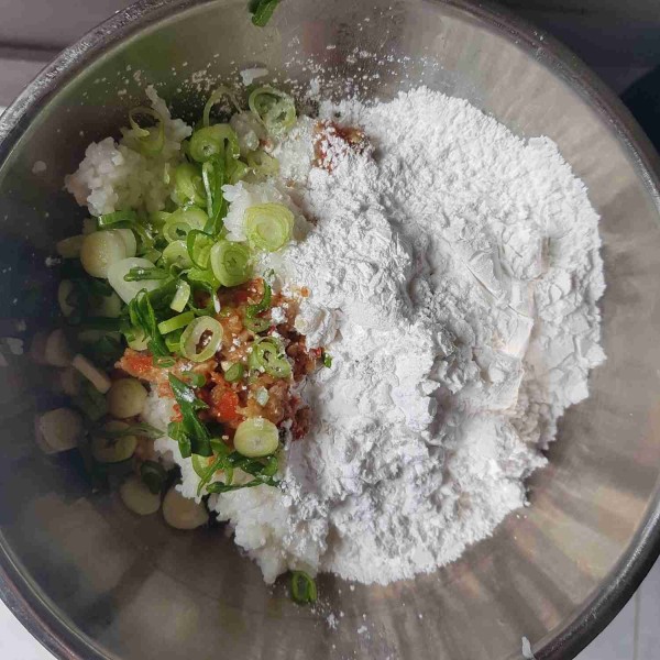 Tambahkan tepung tapioka, irisan daun bawang, dan bumbu ulek yang terdiri dari bawang putih, cabai rawit merah, ketumbar bubuk, merica bubuk, garam, dan kaldu jamur bubuk. Aduk rata sebentar saja.
