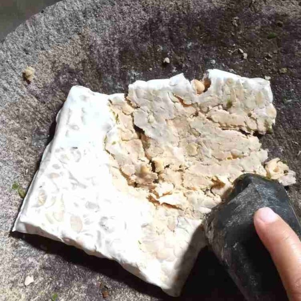 Tumbuklah tempe yang telah di kukus.