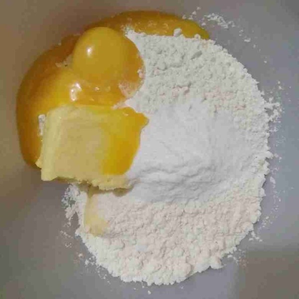 Masukkan tepung terigu, margarin, kuning telur, dan gula halus ke dalam wadah.