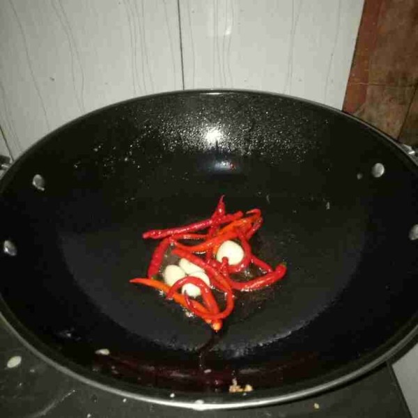 Kupas bawang putih, tusuk-tusuk cabe merah lalu goreng sampai layu dan matang.