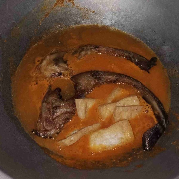 Tambahkan sedikit air, masukkan lele dan tahu yang sudah digoreng. aduk rata sampai meresap ke dalam daging lele.