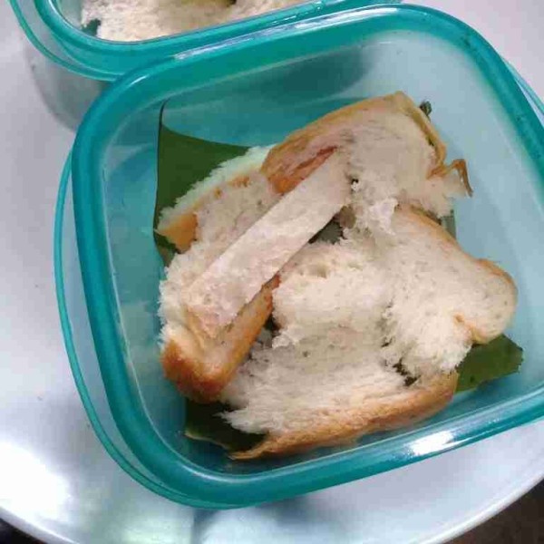Siapkan wadah tahan panas kemudian alasi dengan daun pisang, lalu masukkan roti tawar.