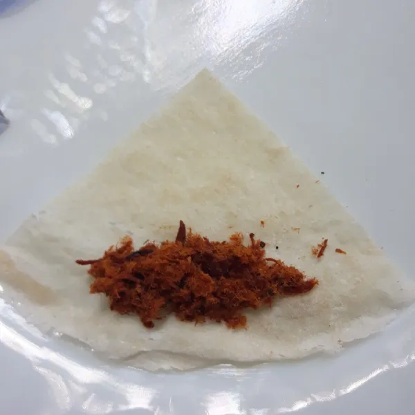 Letakkan selembar kulit lumpia kemudian beri sedikit abon.