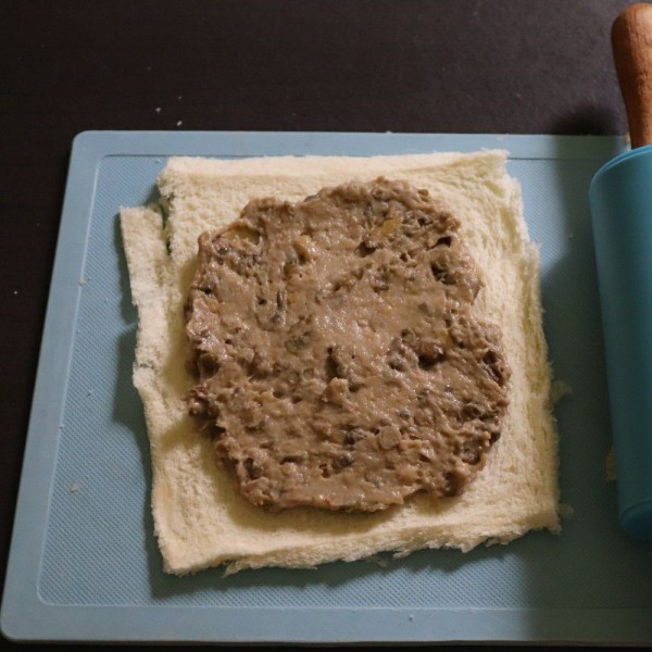 Siapkan roti tawar kemudian gilas menggunakan rolling pin. Beri isian kacang hijau yang telah direbus sampai lunak