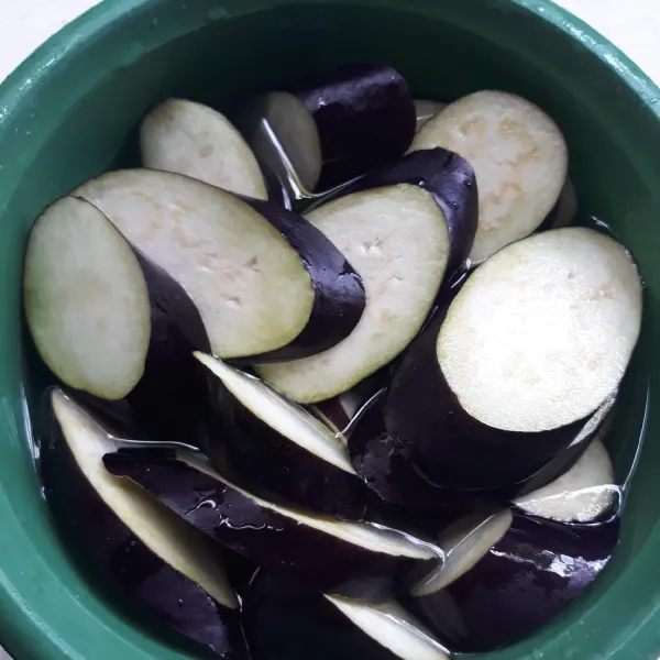 Potong tipis terong dan nrendam di dalam air supaya terong tidak hitam.