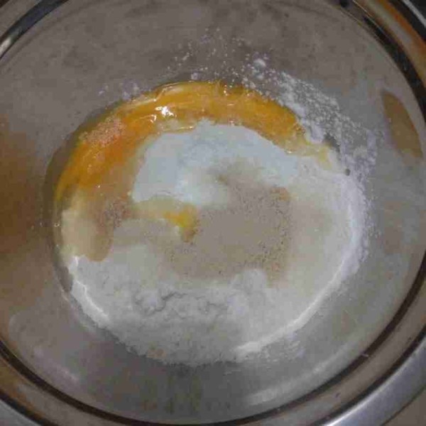 Siapkan mangkok, masukkan tepung terigu, maizena, gula pasir, susu bubuk, ragi instant, dan telur. Aduk hingga merata.