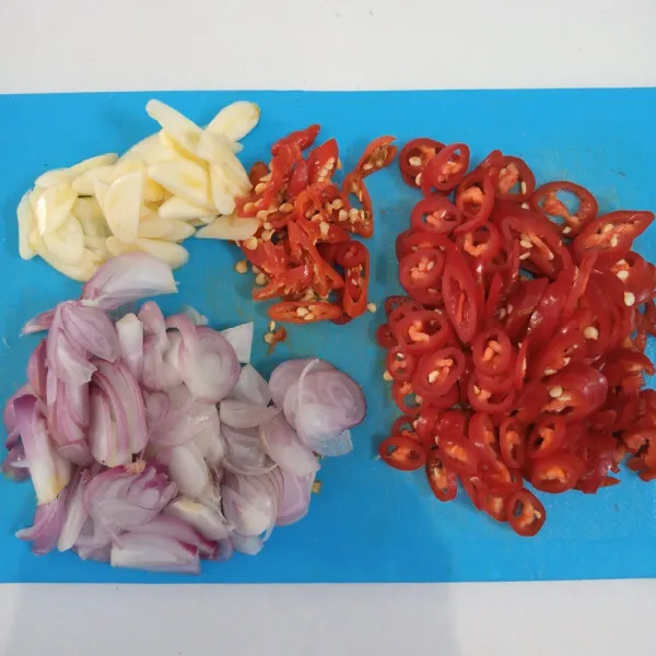 Iris tipis bawang merah, bawang putih, cabai merah, dan cabai rawit.