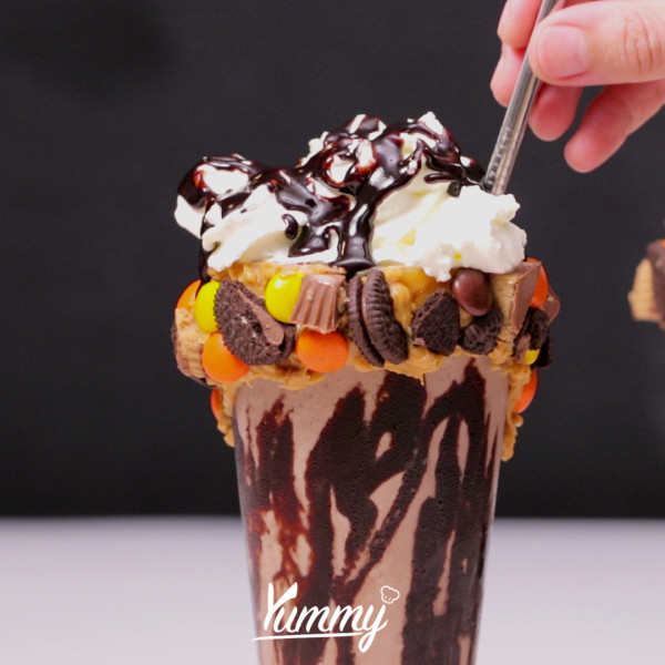 Tambahkan whip cream di atasnya, kemudian beri topping saus coklat, dan potongan coklat sesuai selera. Snickers Peanut Butter Milkshake siap untuk disajikan.