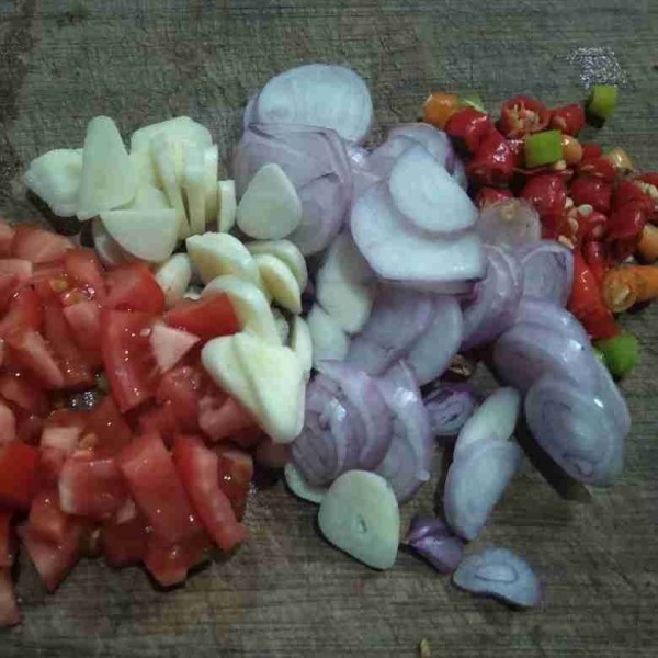 Potong-potong tomat cabe rawit, bawang merah, dan bawang putih.