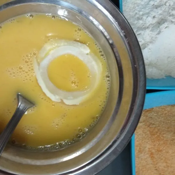 Celupkan bawang bombay ke dalam telur kocok.