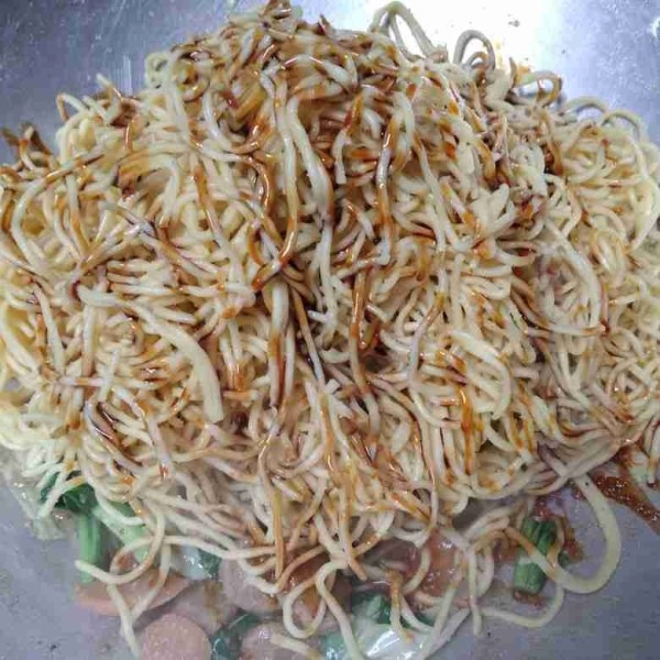 Masukkan mie kuning, beri kecap dan aduk rata.