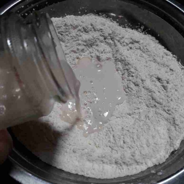 Buat lubang di dalam tepung, masukkan bahan biang, aduk rata dengan tangan.