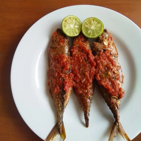 Tata ikan pindang asap di atas piring kemudian tuang sambal di atasnya. Siap disajikan