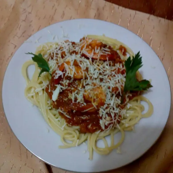 Sajikan spaghetti bersama saus pasta di atasnya dan beri taburan keju parut