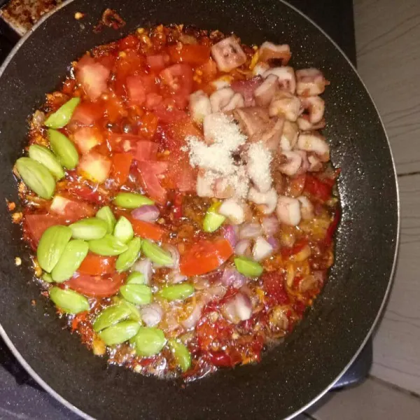 Masukkan semua bahan. Tomat, petai, bawang merah potong dadu, cumi, garam, gula dan kaldu bubuk. Aduk rata. Masak sampai tomat layu, angkat dan sajikan dengan nasi hangat