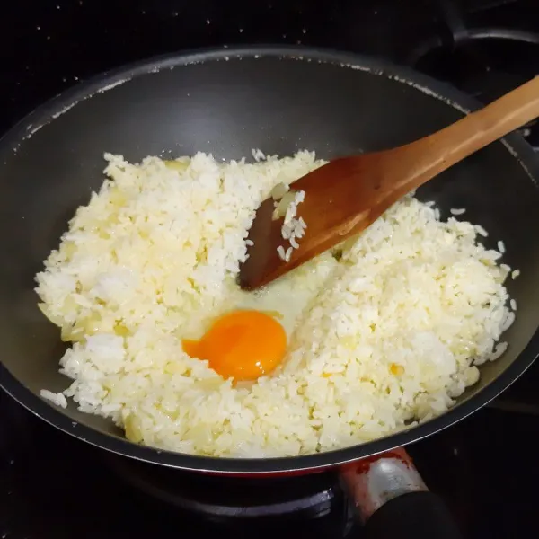 Masukkan nasi. Lalu buat lubang di tengah, kemudian masukan telur. Aduk-aduk