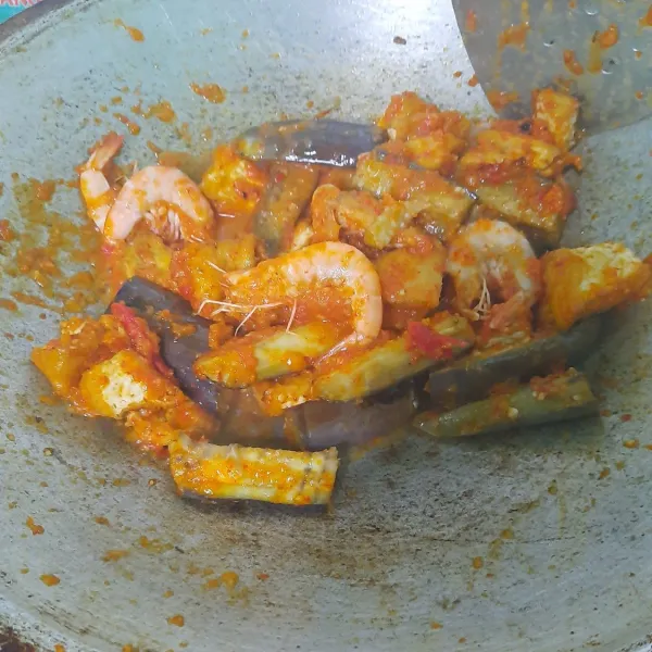 Masukkan udang, aduk sebentar. Masukkan terong dan tahu, aduk lalu masukan gula dan garam. Masak hingga matang, sajikan