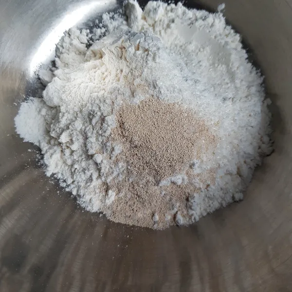 Siapkan wadah. Masukkan tepung terigu, ragi, gula pasir dan garam. Aduk hingga rata