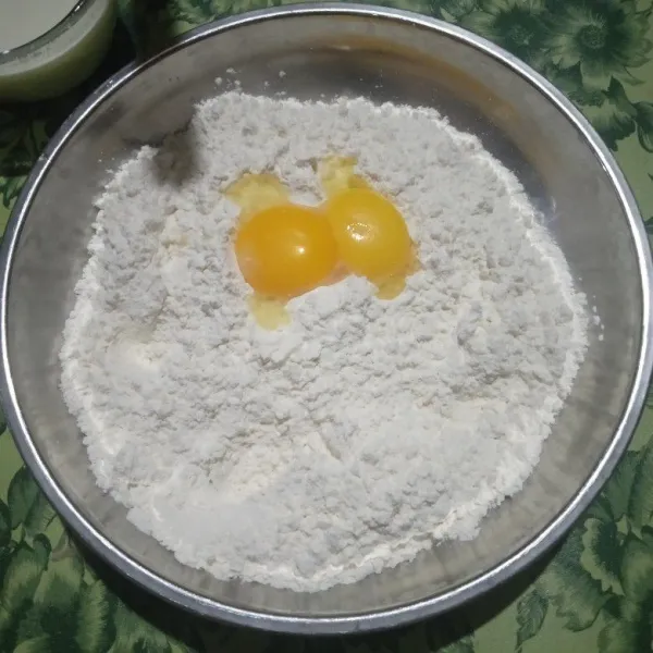 Campur tepung terigu, gula, dan garam ke dalam mangkuk besar kemudian aduk rata lalu tambahkan kuning telur dan susu cair. Uleni hingga rata.
