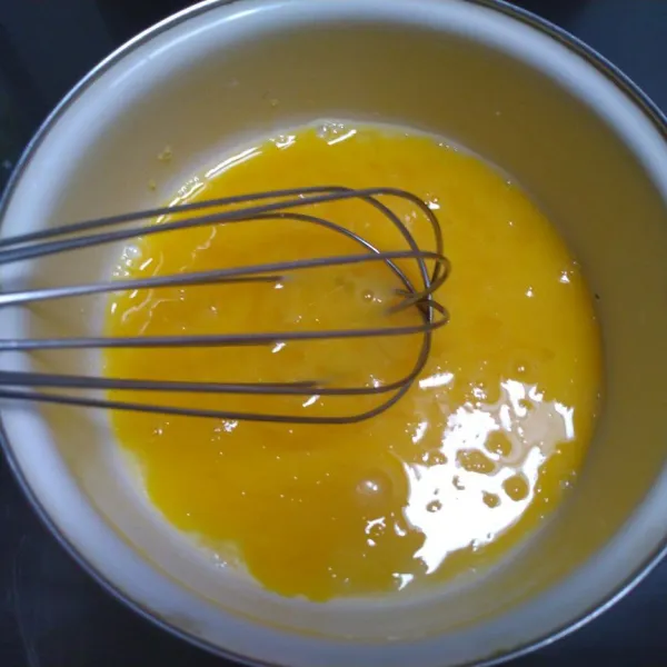 Campurkan gula pasir dan telur. Aduk dengan whisk hingga gula larut.