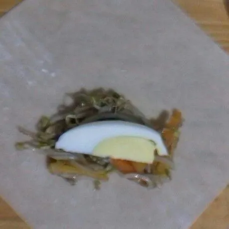 Beri sesendok isian, dan seiris telur. Lipat bentuk amplop, olesi ujung lipatan dengan putih telur.