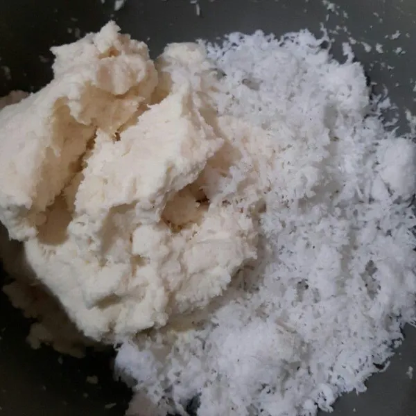 Parut ubi kayu lalu peras agar adonan tidak terlalu basah kemudian masukan kelapa parut dan 1/2 sdt garam. Aduk rata.