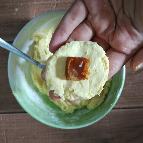 Ambil satu sendok makan adonan, pipihkan, dan isi dengan gula merah ditengahnya. Tutup dan bentuk bulat. Lakukan hingga semua adonan habis.