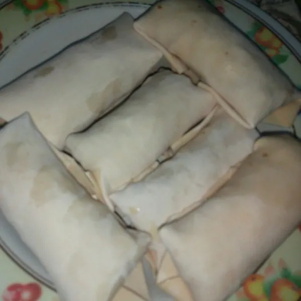 Isi pangsit dengan mie lalu gulung seperti menggulung lumpia, gunakan telur kocok sebagai perekat.