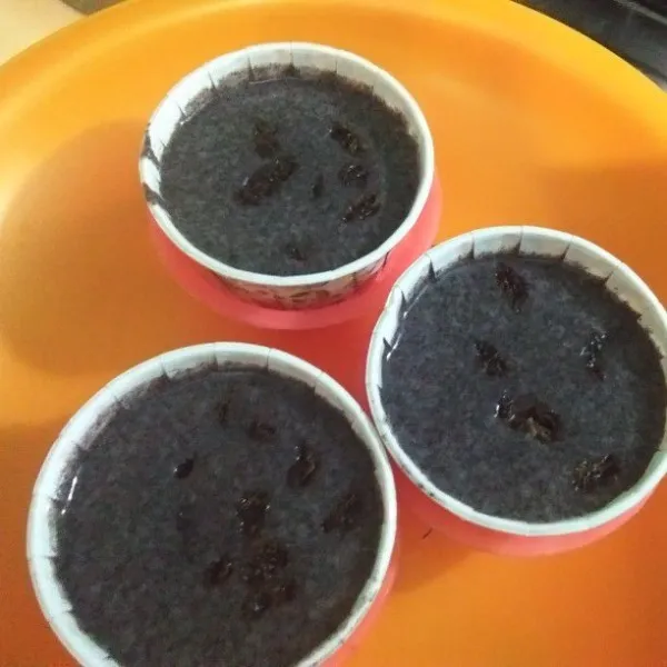 Siapkan paper cup untuk kue kukus atau bisa pakai baking paper. Tuang adonan kemudian tambahkan kismis.