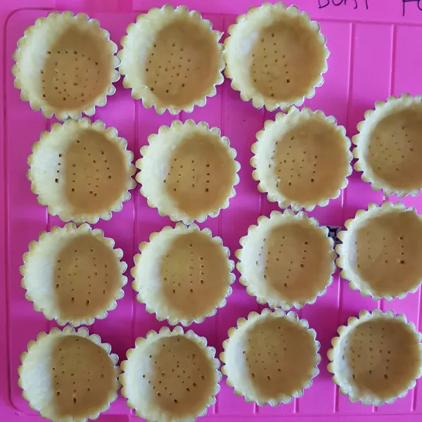 Oles tipis cetakan pie dengan margarin kemudian ambil secukupnya adonan crust dan cetak di cetakan pie. Lakukan hingga adonan habis kemudian tusuk-tusuk adonan.