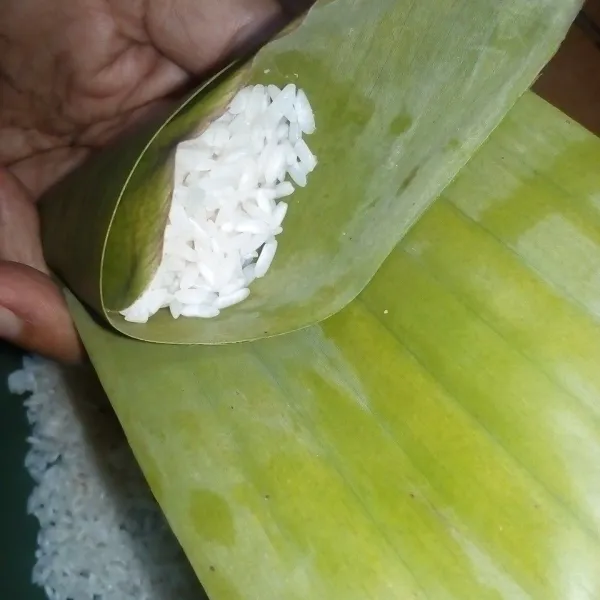 Bungkus beras ketan menggunakan daun pisang.