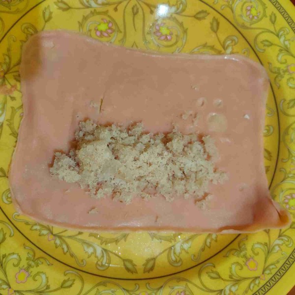 Beri isian/unti kelapa, kemudian lipat menyerupai amplop lalu gulung hingga rapi.