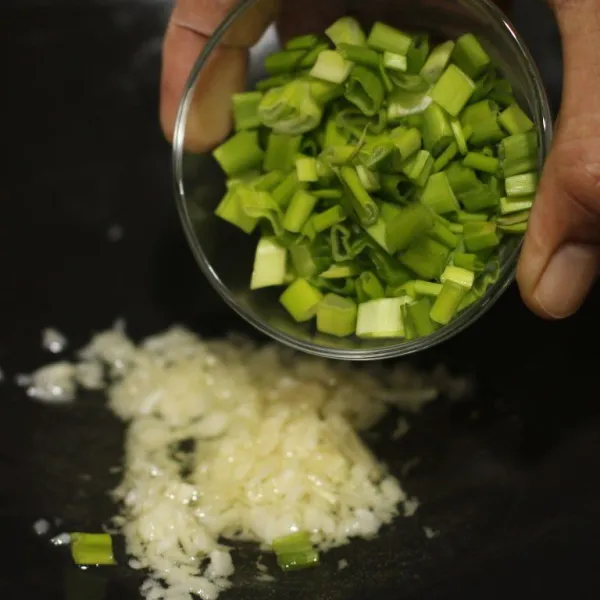 Tumis bawang putih hingga harum kemudian masukkan daun bawang tumis hingga layu.