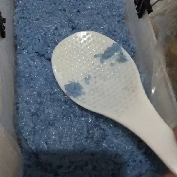 Siapkan wadah yang dilapis plastik dan sudah diolesi minyak. Masukkan ketan biru ke dalam wadah tersebut.