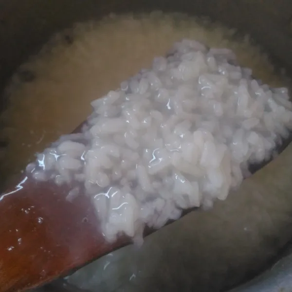 Masak hingga air menyusut sambil terus diaduk supaya tidak gosong bagian bawahnya, tambahkan air lagi secara bertahap hingga beras empuk dan matang.