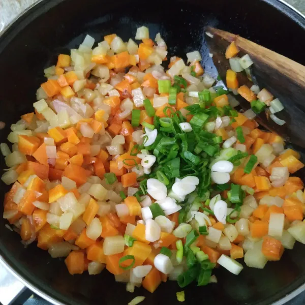 Masukkan kentang dan wortel yang sudah dikukus. Masukkan juga irisan daun bawang.