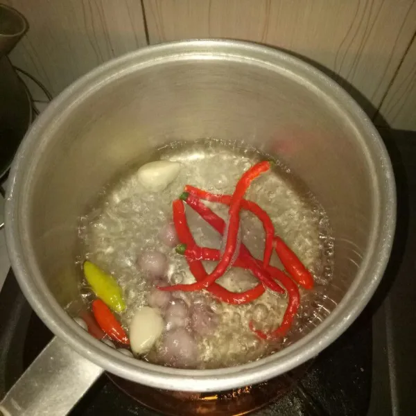 Siapkan panci dan didihkan air. Rebus cabai merah, cabai rawit, bawang merah dan bawang putih