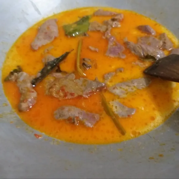 Tambahkan santan dan garam. Biarkan santan mendidih dan mengempukkan daging. Gunakan api kecil